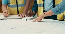 Construction team discussing updates to approved building plans for Gateway 2 compliance.